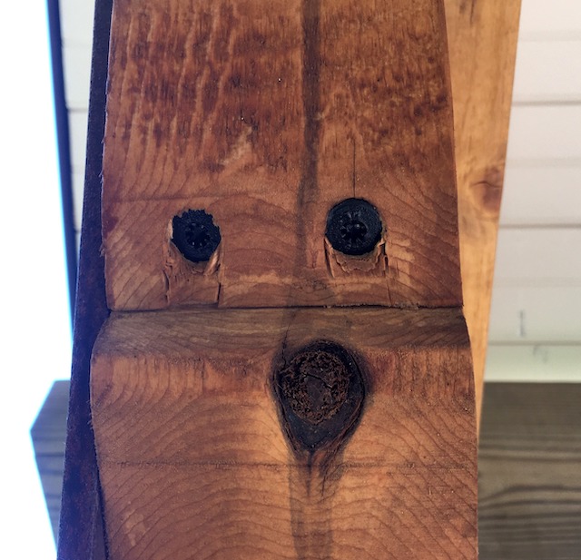 一块木头的照片，上面有漩涡和结，形成了看起来像脸的东西。