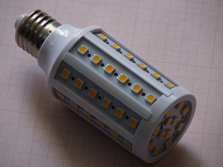 一张白色的LED玉米灯泡的照片，上面放着黄色的LED片，放在一张栅格的纸上。